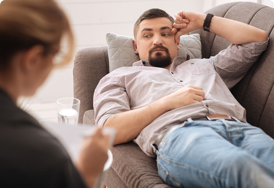 A man reclines on a couch at a counseling session