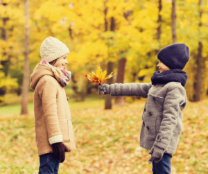 A boy gives a girl a bouquet of autumn leaves