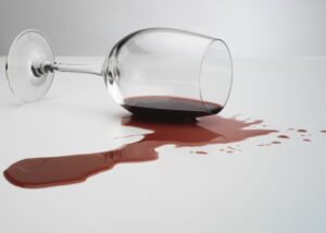 A tipped wine glass that has spilled on the floor